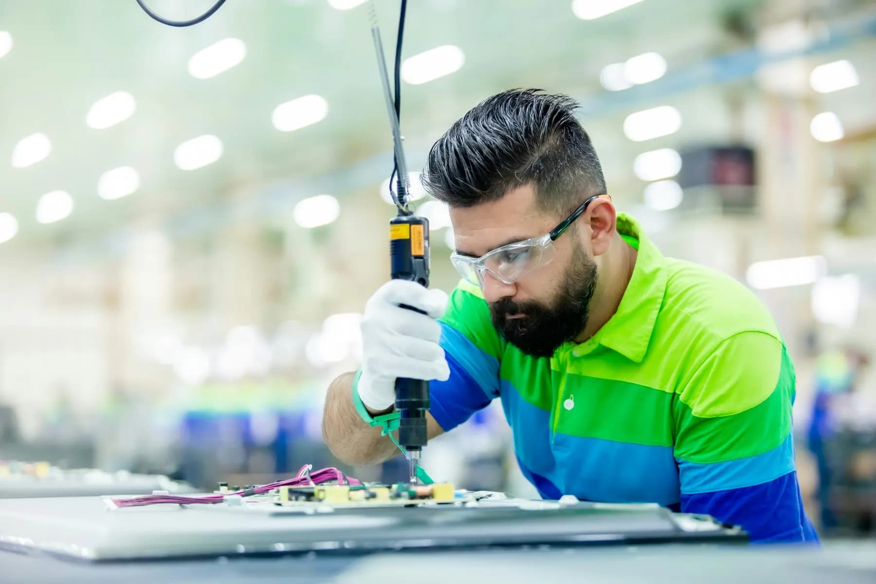 Technician in safety glasses working on equipment on a factory floor
